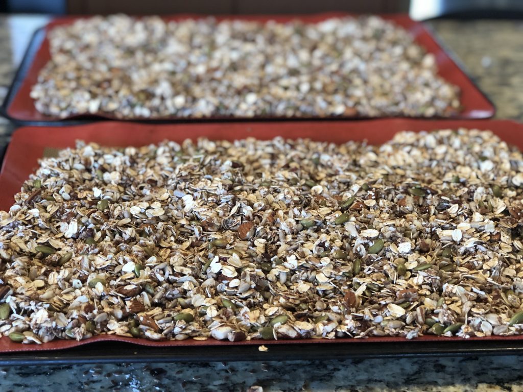 granola mixture spread out on cookie sheet