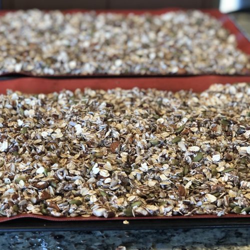 granola mixture spread out on cookie sheet
